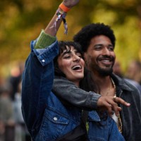 smiling man with arm around girlfriend raising hand - concert stock-fotos und bilder