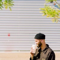 smiling man with coffee to go in front of industrial building - junk food stock pictures, royalty-free photos & images