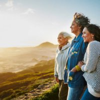 smiling mature friends standing arm in arm by a scenic coast during a road trip - travel stock pictures, royalty-free photos & images