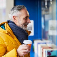smiling mature man at a stall with takeaway coffee - junk food stock pictures, royalty-free photos & images