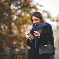 smiling mid adult woman online messaging outdoors. - fashion stock pictures, royalty-free photos & images