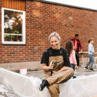 smiling mother looking at hand tool while family working in background during summer - home decoration stock pictures, royalty-free photos & images