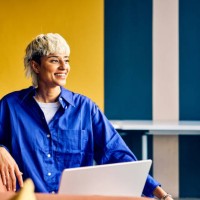 smiling professional asian woman in a blue blouse engaging in a business meeting with a colleague. creative office setting and team interaction concept - fashion stock pictures, royalty-free photos & images