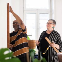 smiling senior couple hanging painting on wall at home - home decoration stockfoto's en -beelden