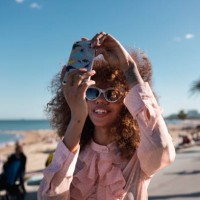 smiling stylish young woman taking a selfie at seaside promenade - fashion stock pictures, royalty-free photos & images
