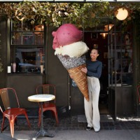 smiling woman carrying large ice cream cone at sidewalk cafe - food stock pictures, royalty-free photos & images