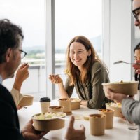 smiling woman enjoying takeaway lunch at work - junk food stock pictures, royalty-free photos & images