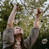 smiling woman hanging lighting equipment in yard during dinner party - garden decoration stock pictures, royalty-free photos & images