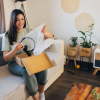 smiling woman opening cardboard package, receiving online store delivery at home - home decoration stock pictures, royalty-free photos & images
