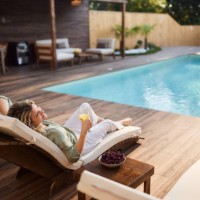 smiling woman relaxing on a lounge chair by the pool. - garden decoration photos et images de collection