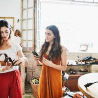 smiling woman using smartphone to take picture of shoe while shopping with friend in boutique - fashion stock pictures, royalty-free photos & images