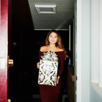 smiling woman walking into home with present for holiday party - fashion stock pictures, royalty-free photos & images