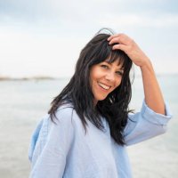 smiling woman with hand in hair at beach - hairstyle stockfoto's en -beelden
