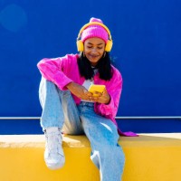 smiling woman with headphones using smart phone on wall - fashion stock pictures, royalty-free photos & images