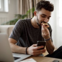 smiling young man using social media at home - junk food stock pictures, royalty-free photos & images