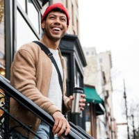 smiling young man walking down stairs in city - fashion stock pictures, royalty-free photos & images
