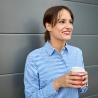 smiling young white caucasian woman on the move drinking coffee from disposable cup. - junk food stock pictures, royalty-free photos & images