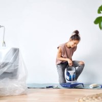 smiling young woman pouring paint in paint tray while kneeling at home - home decoration stock pictures, royalty-free photos & images