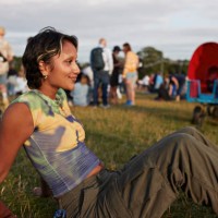 smiling young woman sitting on grass at festival - concert stock pictures, royalty-free photos & images