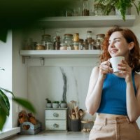 smiling young woman standing with coffee cup at home - coffee stock pictures, royalty-free photos & images