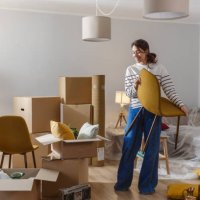 smiling young woman surrounded by boxes while moving, unpacking personal belongings - home decoration stock pictures, royalty-free photos & images