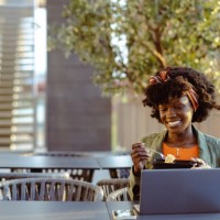 smiling young woman using laptop during the lunch break - junk food stock pictures, royalty-free photos & images