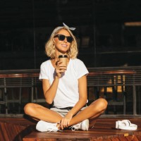 smiling young woman with cell phone and takeaway drink at the cafe - junk food stock pictures, royalty-free photos & images