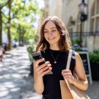smiling young woman with smartphone walking on the street - fashion stock pictures, royalty-free photos & images