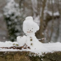 snowman and tree branches made on the wall of the city park on a snowy day - garden decoration stock pictures, royalty-free photos & images