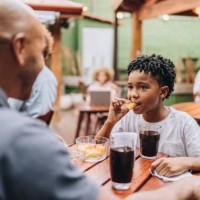 son eating and talking with father at restaurant - junk food stock pictures, royalty-free photos & images