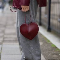 Sonia Lyson wears ballerinas and burgundy heart shaped bag Alaia, grey wide leg jeans Levis, leather shirt Gant on the way to Gmbh during the Berlin...