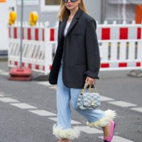 Sonia Lyson wears black oversized striped blazer, blue Louis Vuitton bag, wide leg denim jeans with fringes, pink shoes, Tom Ford sunglasses during...