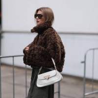 Sophia Geiss is seen wearing squared black aviator sunglasses with olive lenses from Vehla Eyewear, a silver nose ring, a cropped brown faux...