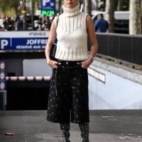 Sophia Roe is seen wearing a cream sleeveless sweater, black and white print shorts, skinny belt, black and gray Chanel boots and black...