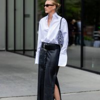 Sophie Sss wears white oversized button shirt, black white bag, black high waisted leather skirt, brown Nike sneakers at Oslo Fashion Week 2024 on...