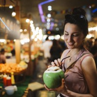souriante jeune femme ayant une eau délicieuse et fraîche de noix de coco sur le pouce - food photos et images de collection