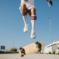 sportive man jumping above ground with skateboard performing trick - fashion stock-fotos und bilder