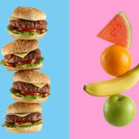 stack of hamburgers and stack of fruit - junk food stock pictures, royalty-free photos & images