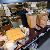 staff in restaurant kitchen preparing and packaging food for delivery during covid-19 pandemic - junk food stock pictures, royalty-free photos & images