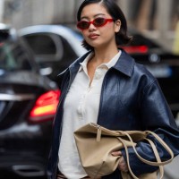 Stephanie Hui wears black leather jacket, brown bag, striped shorts, white polo outside Lacoste during Womenswear Spring/Summer 2025 as part of Paris...
