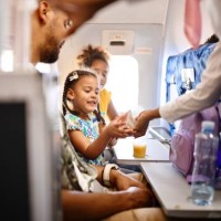 stewardesses serving food and drinks to family on the airplane during flight - food stock pictures, royalty-free photos & images