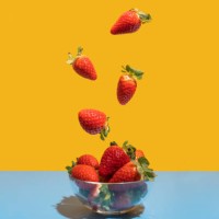 strawberries flying in the bowl on the blue-yellow background - food stock pictures, royalty-free photos & images