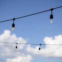 string lights against a blue sky with white puffy clouds - garden decoration stock pictures, royalty-free photos & images