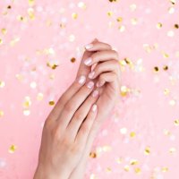 stylish female pink and white manicure. beautiful young woman's hands on pink pastel background with festive multicolored confetti. trendy geometric pattern. art manicure. - nails art stock pictures, royalty-free photos & ima