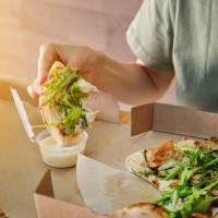 stylish girl adds sauce to a slice of vegetarian pizza. italian cuisine. sliced pizza in paper packaging on a wooden table. delicious lunch, snack, fast food. - junk food stock pictures, royalty-free photos & images