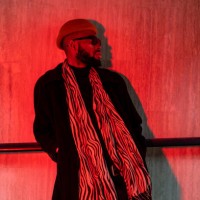 stylish hipster black man in sunglasses stands leaning against wall in underpass lit by red light - fashion stock pictures, royalty-free photos & images