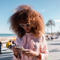 stylish young woman using cell phone at seaside promenade - fashion stock-fotos und bilder