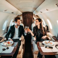 successful couple making a toast with champagne glasses while having canapes aboard a private airplane - travel stock pictures, royalty-free photos & images