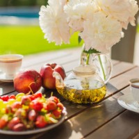 summer breakfast outside. green tea in teapot on wooden table. white peonies in vase. fruits on plate. fresh bakery. back yard of house. - garden decoration stock pictures, royalty-free photos & images