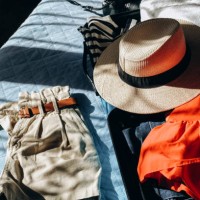 summer clothes in a suitcase luggage for travel, shadow overlay . french style t-shirt with stripes and straw summer hat. - fashion stock pictures, royalty-free photos & images